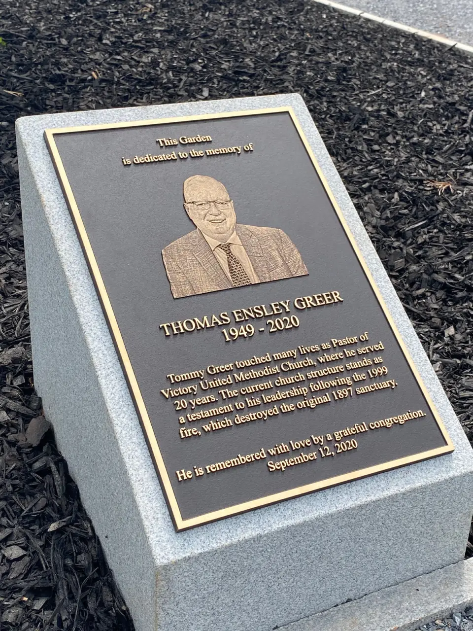 A bronze plaque with a portrait, mounted on a grey granite base