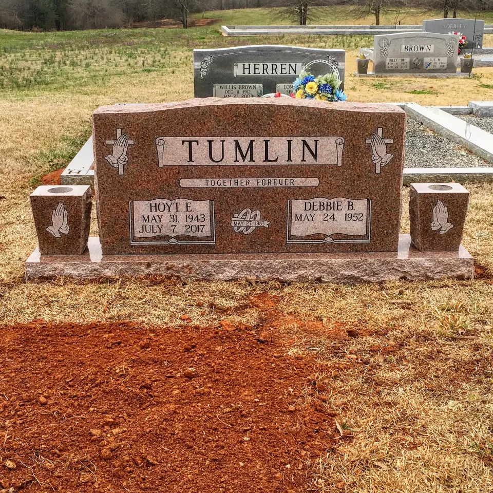 A red granite companion upright with vases, set in Georgia clay