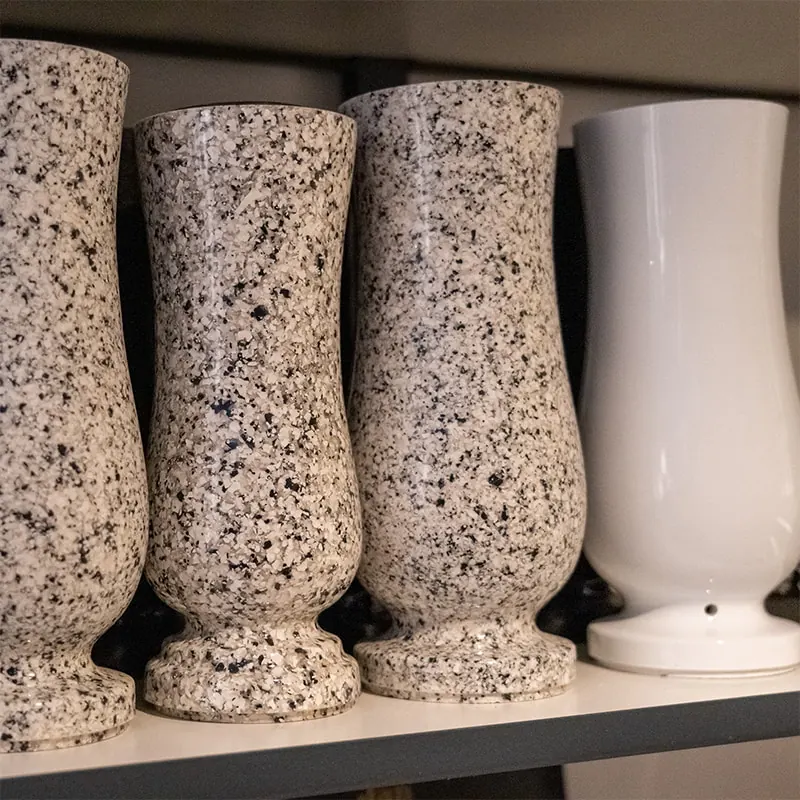 Speckled granite and white memorial vases on a shelf