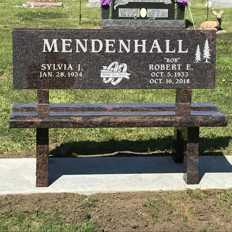 Mahogany granite memorial bench engraved with two names and pine trees