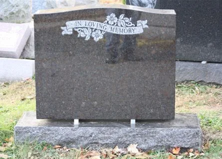 Dark granite upright headstone with an In Loving Memory banner and carved flowers